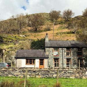 an old stone house with a stone wall at Terfyn Cottage in Dinorwic