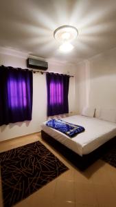 ein Schlafzimmer mit einem großen Bett mit lila Vorhängen in der Unterkunft Warzazat Apartments in Ouarzazate