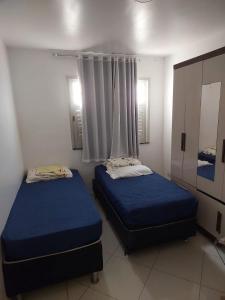2 Betten in einem Zimmer mit blauer Bettwäsche und einem Fenster in der Unterkunft CASA próximo PRAIA para temporada in Aracaju