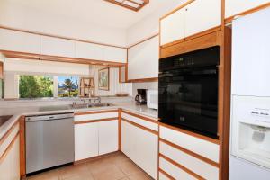 eine Küche mit weißen Schränken und einem schwarzen Gerät in der Unterkunft Manualoha 101 in Kipu