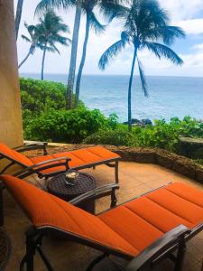 Un patio con mesa y sillas y el mar. en Poipu Makai E1, en Koloa