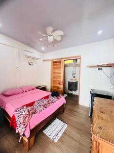 a bedroom with a pink bed and a television at Apartamentos en el Centro de Puerto Viejo in Puerto Limón