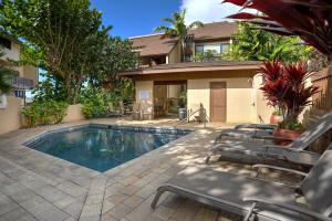 a swimming pool with chairs and a house at Poipu Makai E1 in Koloa