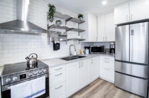 a kitchen with white cabinets and a stainless steel refrigerator at NN - Flats on 4th #3 - Downtown 1-bed 1-bath in Whitehorse