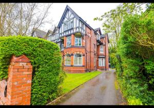 a large brick house with a green hedge in front of it at Cozy 1BDR - Bay Windows & Superb Location in Manchester