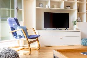 a living room with a blue chair and a tv at Charming 2BR Flat, Holloway Road in London