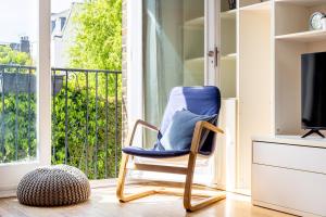 a blue rocking chair in a room with a window at Charming 2BR Flat, Holloway Road in London