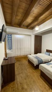 1 dormitorio con 2 camas, escritorio y TV en Mahbubakhon Hotel, en Bukhara