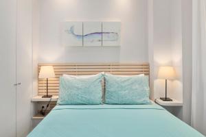 een slaapkamer met een bed met blauwe lakens en 2 lampen bij CasaNova Studios in Corfu-stad