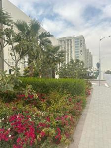 ‘Ūd al Bayḑāʼ的住宿－Apartmán Fiora, 2kk,Dubaj，一条种满鲜花和棕榈树的路边和建筑