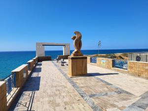 a statue on a walkway near the ocean at Villa Rosa in Balestrate