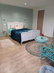 a bedroom with a white bed and a table at un petit studio moderne et conviviale in Banville