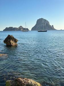 Ibiza Camper Vans في مدينة إيبيزا: اثنين من القوارب في كمية كبيرة من المياه مع الصخور