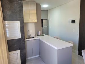 eine Küche mit weißen Schränken und einer weißen Arbeitsplatte in der Unterkunft Apartamento novo luxo, 2 suítes, piscina aquecida no condomínio, 1 quadra do mar, completo in Bombinhas