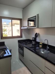 eine Küche mit einer Spüle, einem Herd und einem Fenster in der Unterkunft Apartamento novo luxo, 2 suítes, piscina aquecida no condomínio, 1 quadra do mar, completo in Bombinhas