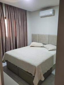 ein Schlafzimmer mit einem Bett und einem Fenster in der Unterkunft Apartamento novo luxo, 2 suítes, piscina aquecida no condomínio, 1 quadra do mar, completo in Bombinhas