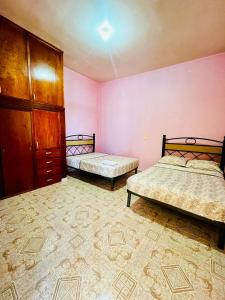 2 Betten in einem Zimmer mit rosa Wänden in der Unterkunft La casa de doña Juanita 
