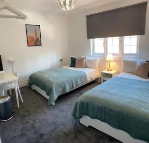 a bedroom with two beds and a desk with a lamp at CAMDEN TOWN PARKWAY ROOMS in London +3 photos