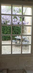 a window view of a patio with a table and chairs at Chambre d'hôtes spacieuse, salle de bain privative in Saint-Michel-de-Fronsac