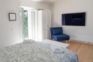 ein Schlafzimmer mit einem Bett und einem blauen Stuhl in der Unterkunft Rustico in pietra in Brissago