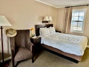 a bedroom with a bed and a chair and a window at Blowing Rock Inn in Blowing Rock