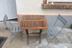 einen Holztisch und zwei Stühle vor einem Gebäude in der Unterkunft Maison + parking. Calme, confort in Rouen