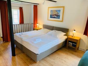 - une chambre dotée d'un grand lit avec des draps et des oreillers blancs dans l'établissement Pension Hessbögel, à Grünendeich