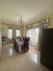 a dining room with a table and chairs and windows at Unity Comfort Home in Rukungiri