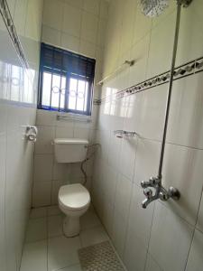 baño blanco con aseo y ventana en Unity Comfort Home, en Rukungiri