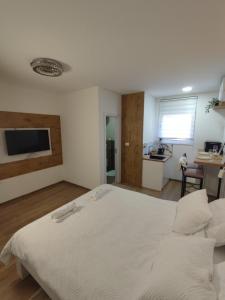 een slaapkamer met een groot wit bed en een keuken bij Apartmani Happy House in Surčin