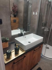 La salle de bains est pourvue d'un lavabo blanc et d'une douche. dans l'établissement Nowy Apartament, à Mińsk Mazowiecki