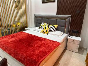 a bed with a red blanket and pillows on it at Your homely studios in Ghaziabad