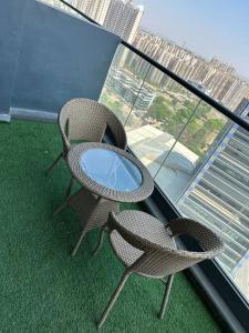 two wicker chairs and a glass table on a balcony at Your homely studios in Ghaziabad