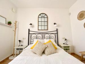 Un dormitorio con una cama blanca con almohadas amarillas. en Montacala Holidays House, en Cumbre del Sol