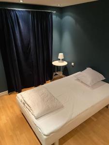 a bedroom with a bed with a black wall and a window at Super sentralt for 2 personer in Lillestrøm