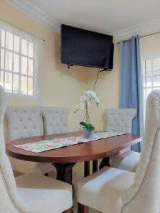 uma mesa de jantar com cadeiras brancas e uma televisão em Villa Familiar en Río San Juan con Wifi BBQ Piscina @drvacationsrental em Río San Juan