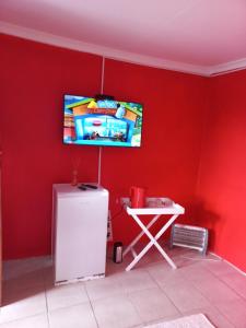 Habitación con pared roja, TV y nevera. en Grey house lodge, en Pietermaritzburg