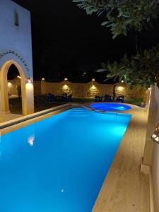 una piscina notturna con illuminazione blu di فيلا الريف السويسري a Tunis
