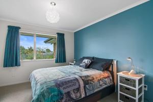 sypialnia z niebieskimi ścianami, łóżkiem i oknem w obiekcie Pohara Beach Life w mieście Pohara