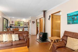 uma sala de estar com dois sofás de couro e uma televisão em Waters Edge Golden Bay em Collingwood
