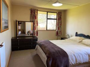 a bedroom with a large bed and a mirror at Kiwi Holidays in Cromwell in Cromwell