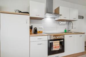 cocina con armarios blancos y fogones en Casa Oasis IV: Modern, Nespresso & Thermennähe, en Bad Füssing