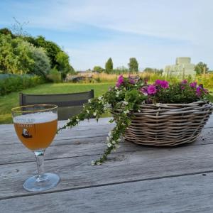 un vaso de cerveza sentado en una mesa de madera con una cesta de flores en B&B Krieken de Jour, en Ninove