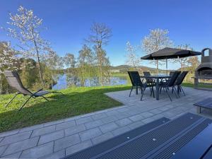 un patio con mesa, sillas y sombrilla en Holiday home with terrace and lake view, en Neunburg vorm Wald