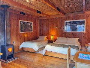 1 Schlafzimmer mit 2 Betten und einem Holzofen in der Unterkunft Hotel Último Paraíso in Cochrane