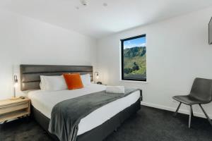 une chambre avec un lit, une chaise et une fenêtre dans l'établissement La Residence du Parc, à Queenstown
