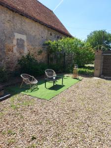 einen Garten mit zwei Stühlen und einer Bank auf einer Wiese in der Unterkunft Douce Campagne in Clermont-Créans