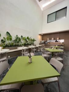 a cafeteria with green tables and chairs and plants at Aura Hotel boutique in Guadalajara