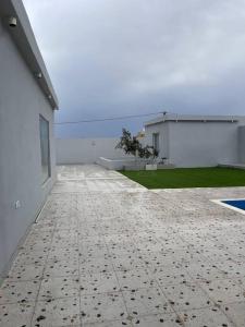 an empty patio of a white building with a yard at شاليه السمو الفندقي in Umm Lujj