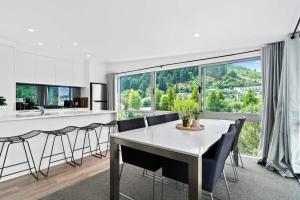 een eetkamer met een tafel en stoelen en een groot raam bij Central Queenstown Luxury in Queenstown